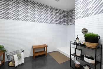 a bathroom with white brick walls and a black shelving unit with a wooden bench and a